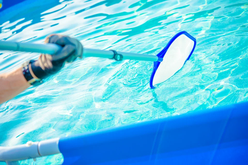 Pool technician using a skimmer net to clean a pool